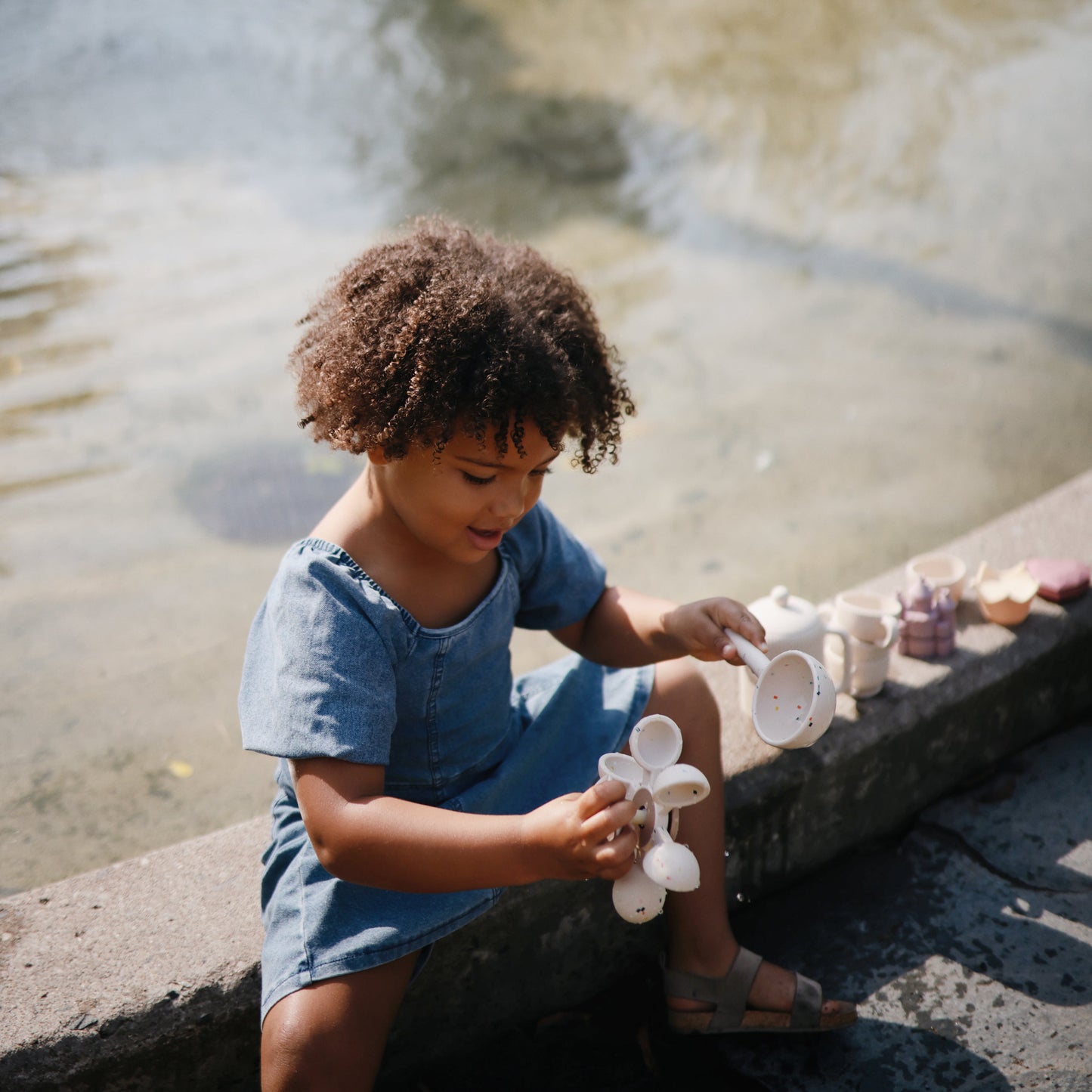 Child playing with silicone toys by a water fountain