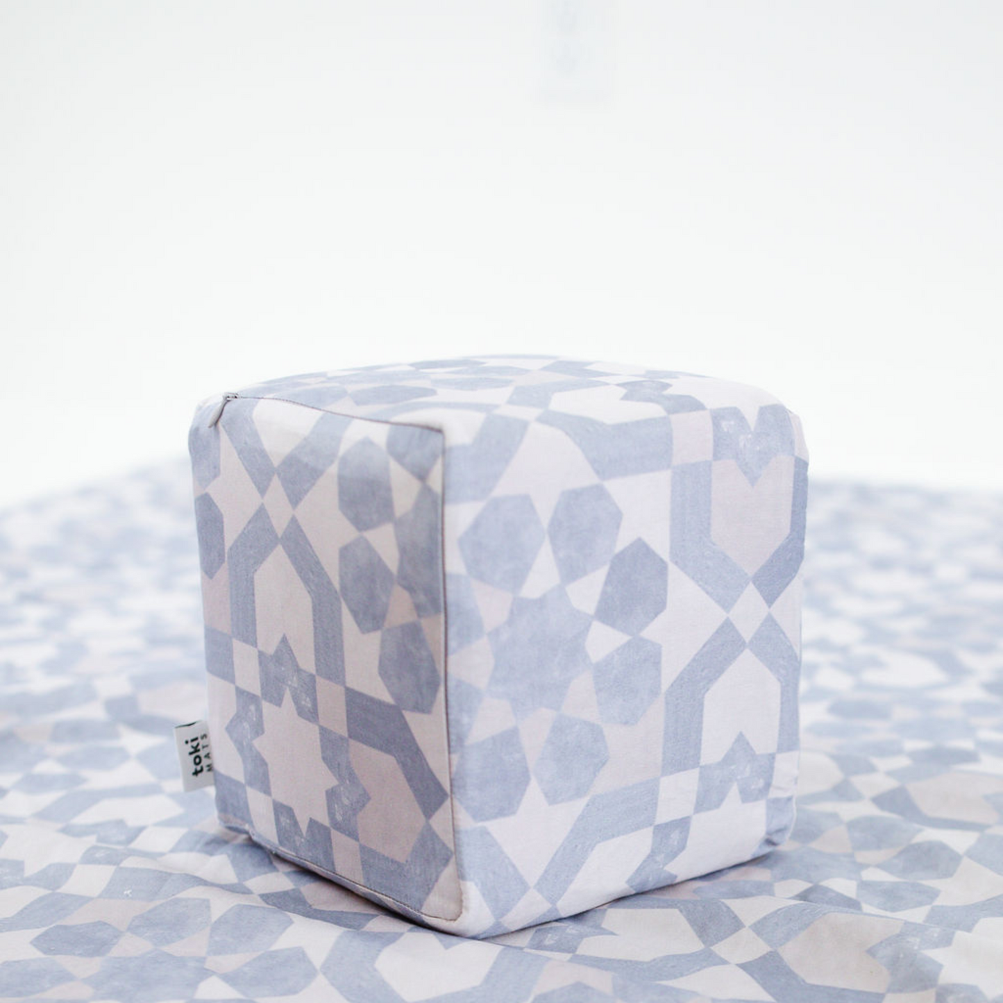 Cube-shaped ottoman with geometric pattern on a matching fabric surface