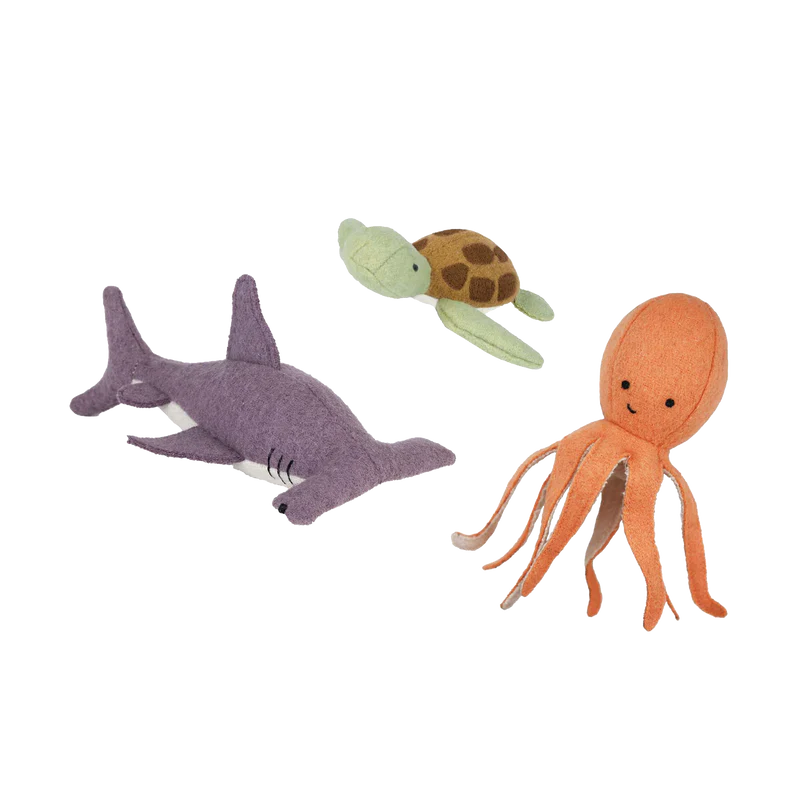 Three plush toy animals representing marine life - an octopus, a turtle, and a shark, all made from a soft wool blend with embroidered features.