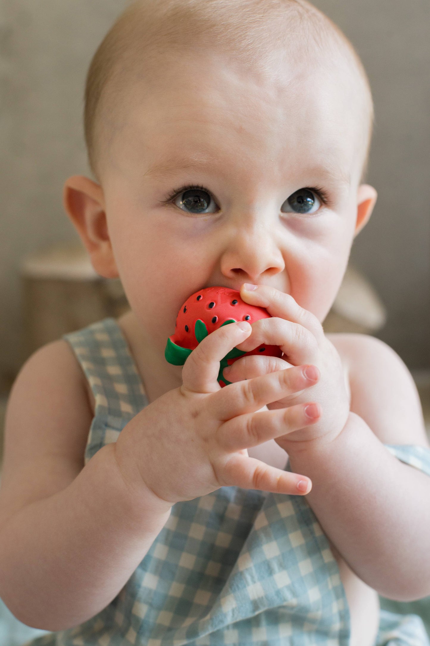 Baby chewing on a strawberry teether.