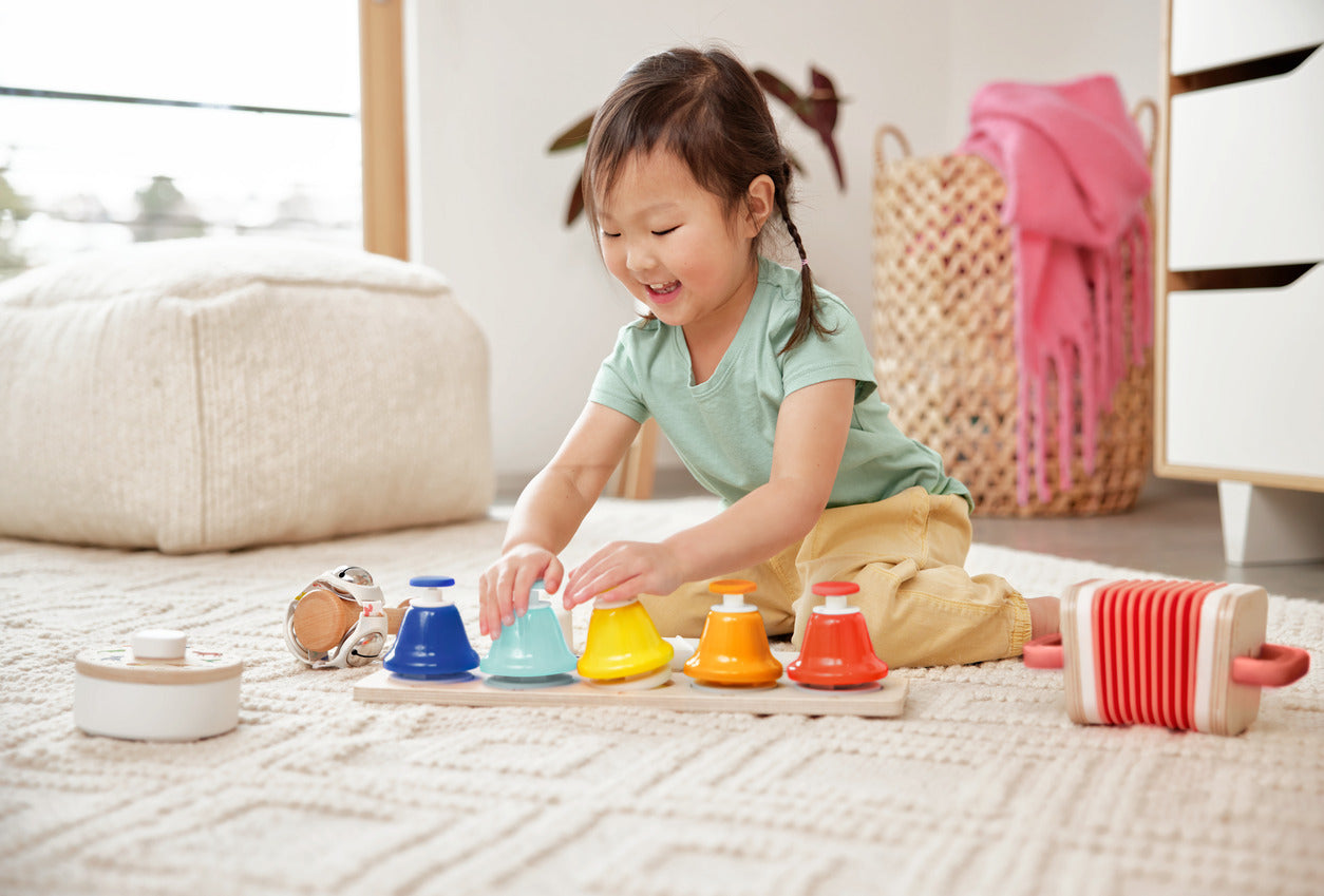 Child playing with colorful wooden toys on a carpeted floor.