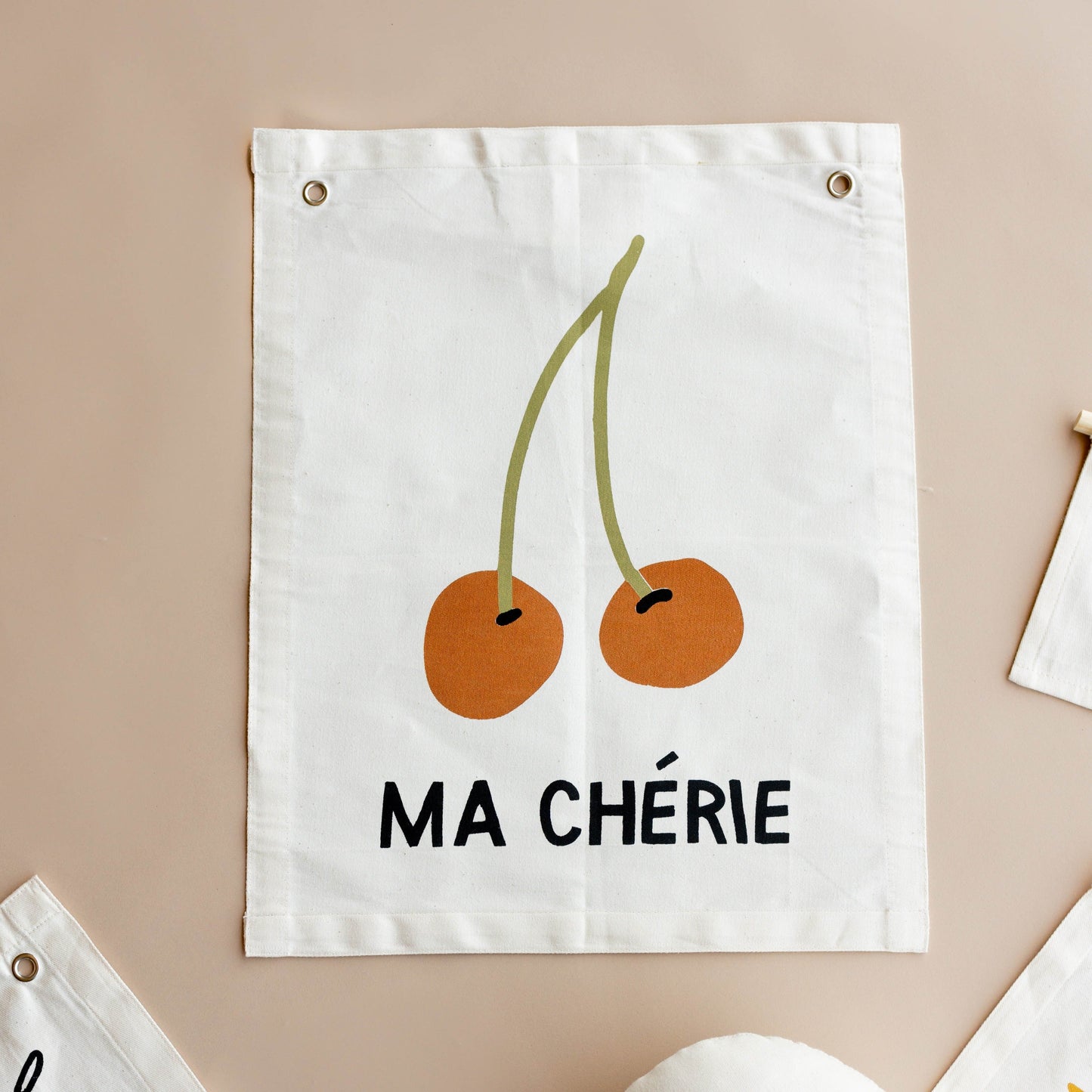 Fabric wall hanging with cherries and 'MA CHÓRIE' text on a beige background