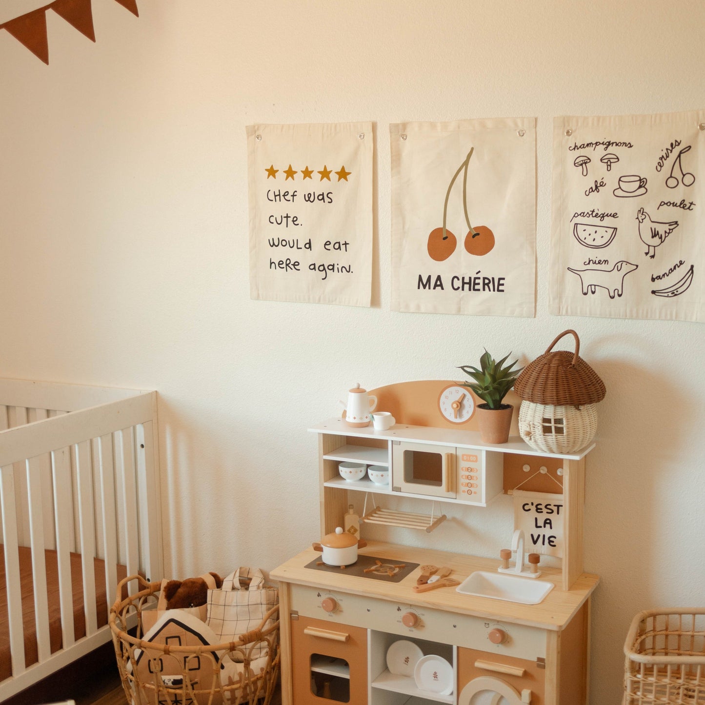 Children's play kitchen set in a room with crib and wall decorations.
