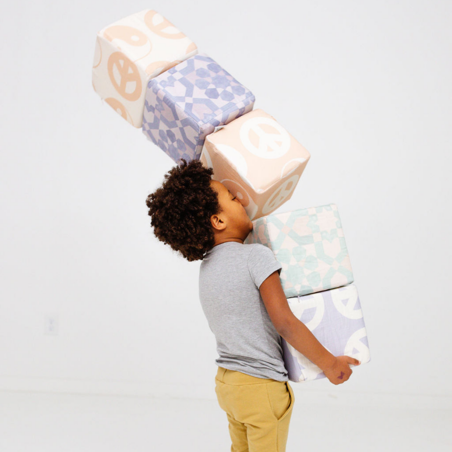 Child balancing colorful blocks on their head against a white background