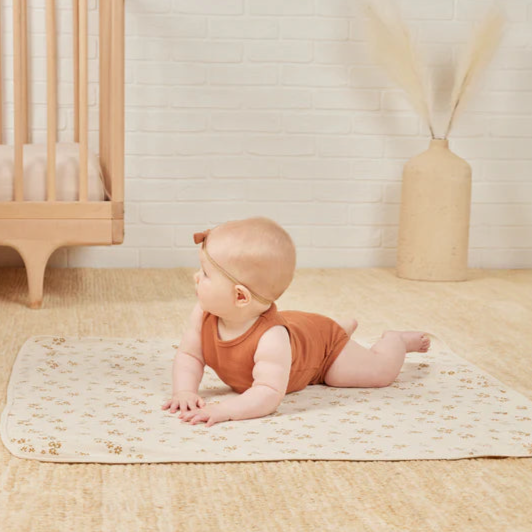 Baby laying on the Quincy Mae beige baby blanket with flowers on it.
