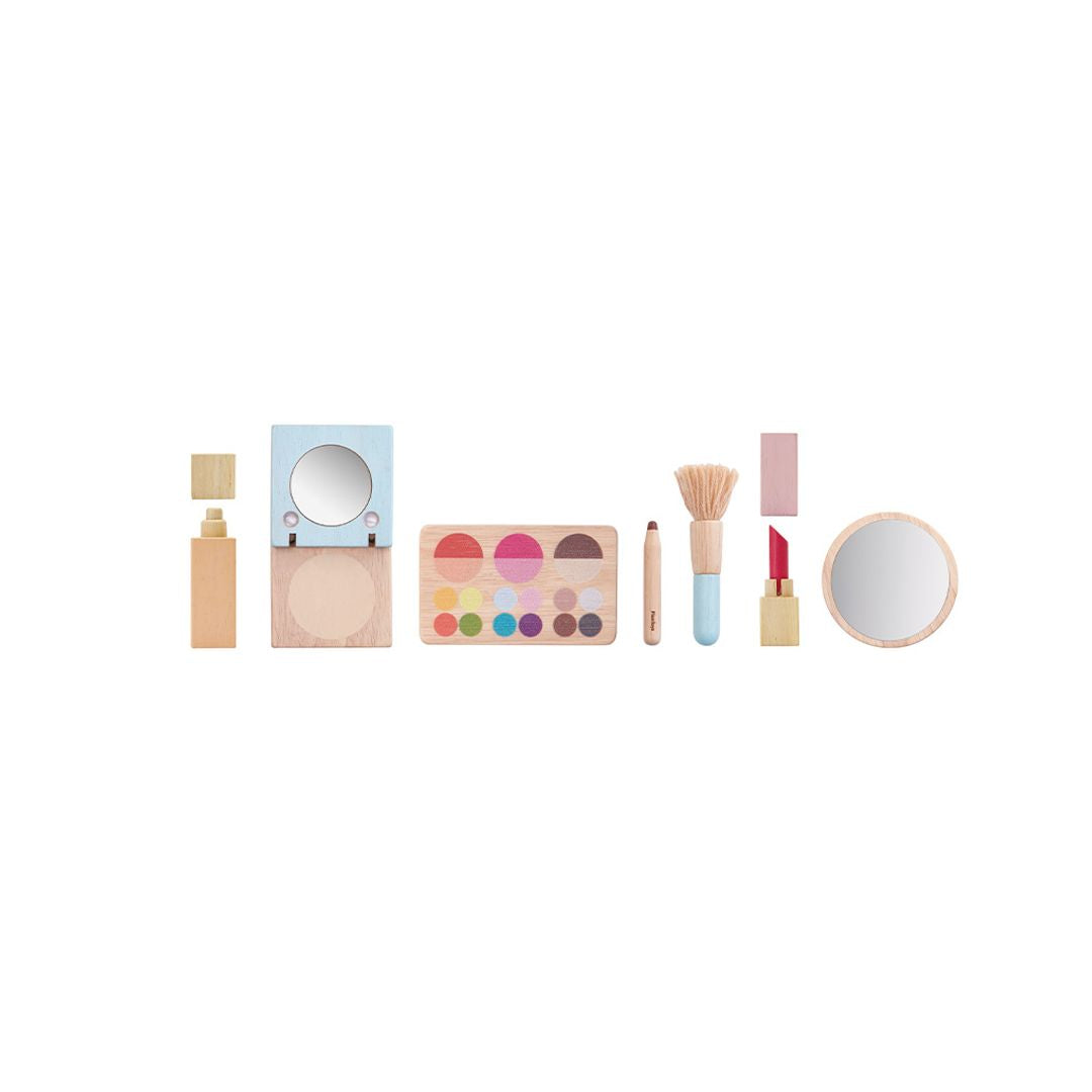 Set of toy makeup items including a mirror, palette, and other accessories on a white background