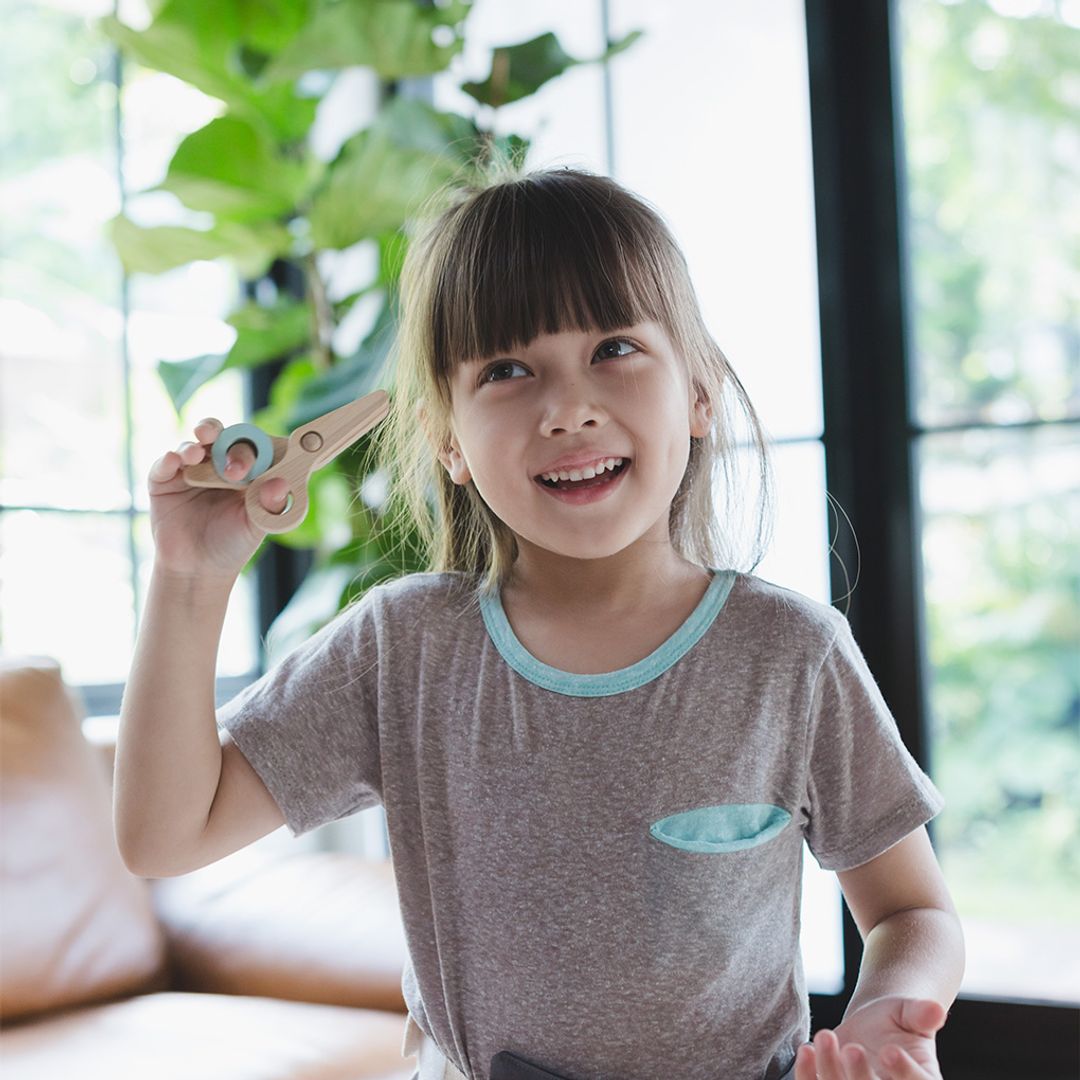 Child holding a pair of scissors with a plant in the background