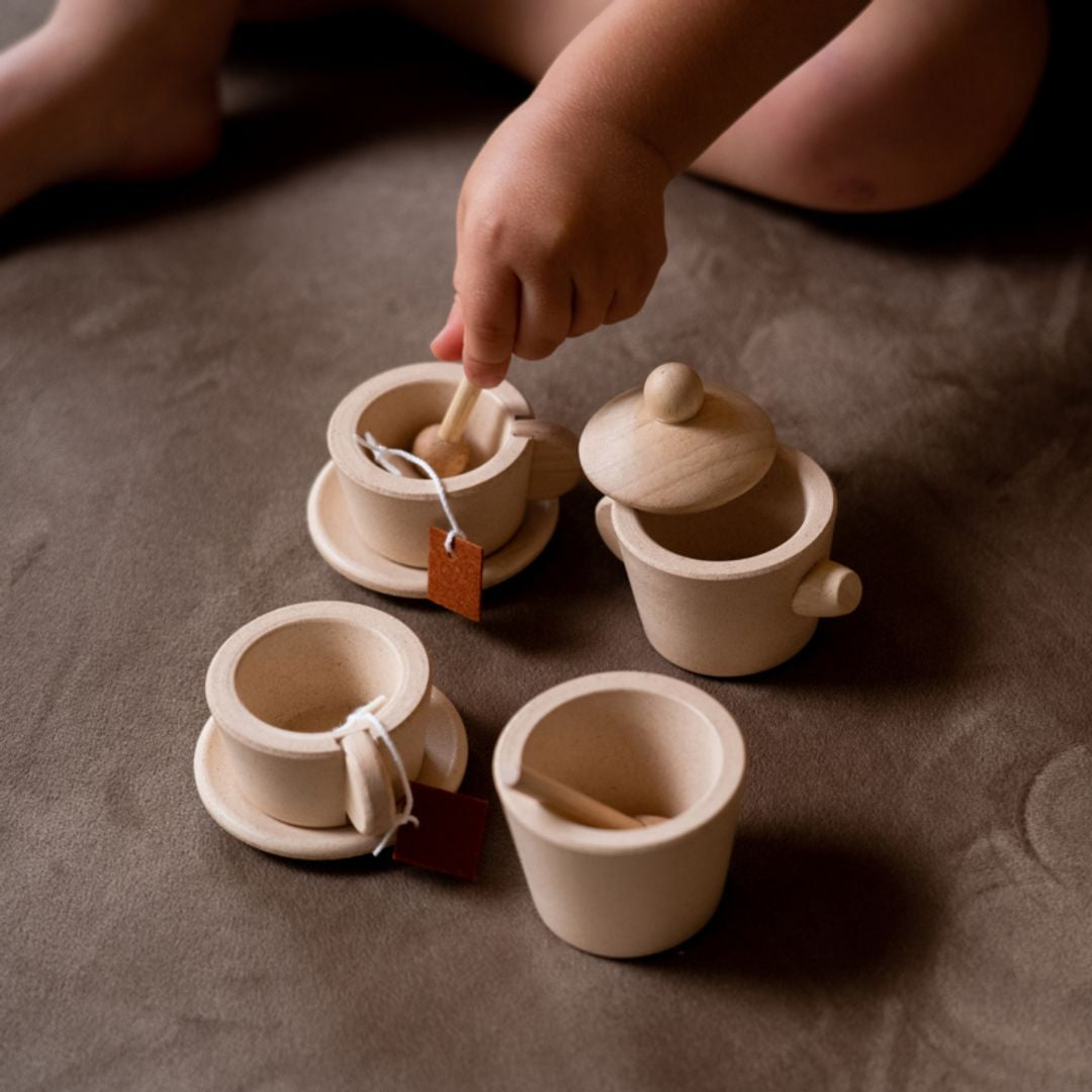 Set of small ceramic pots with lids on a textured surface, child's hand interacting with one pot.