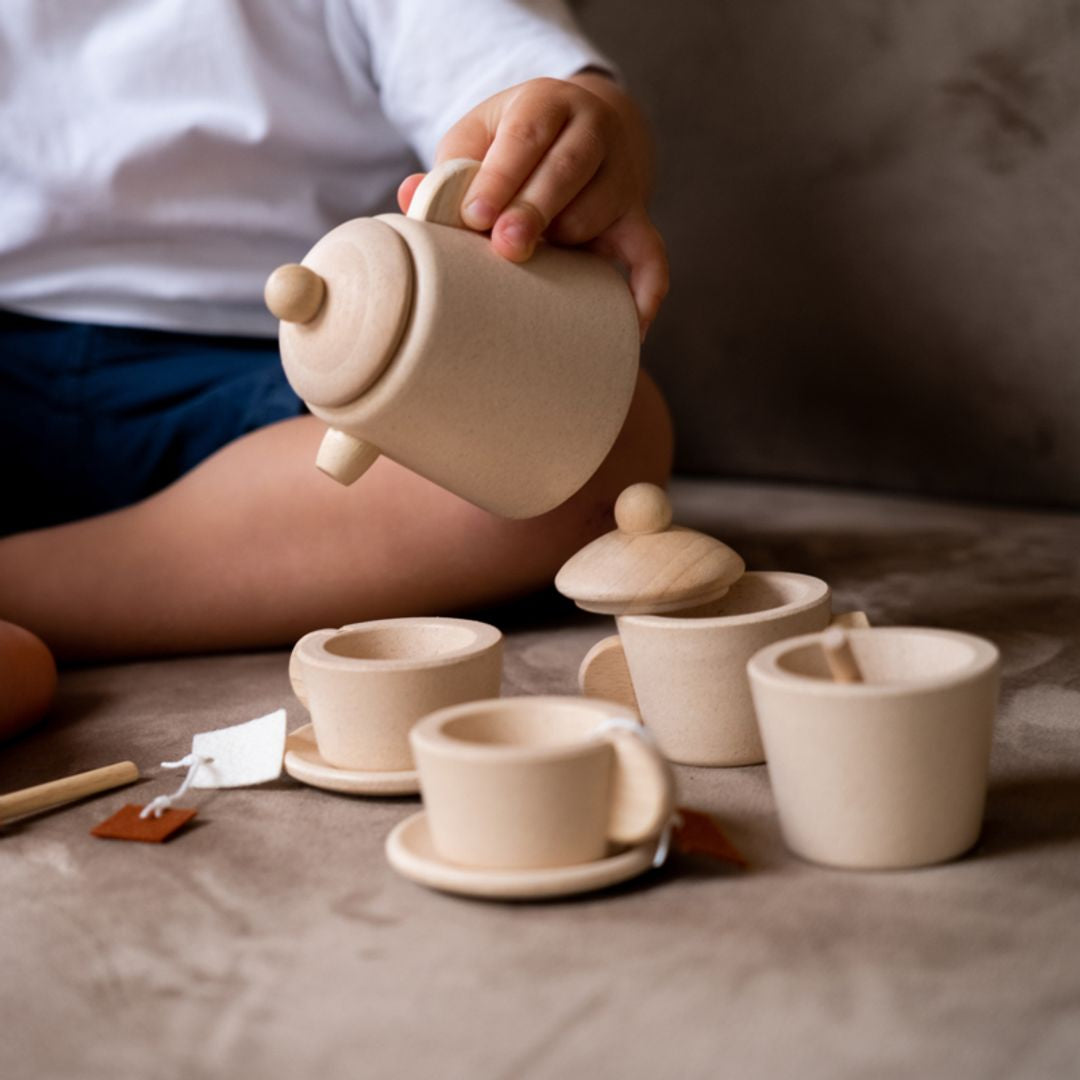 Person playing with a wooden tea set on a soft surface