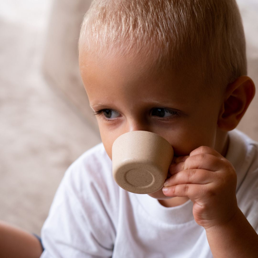 Child holding a small wooden cup close to their face