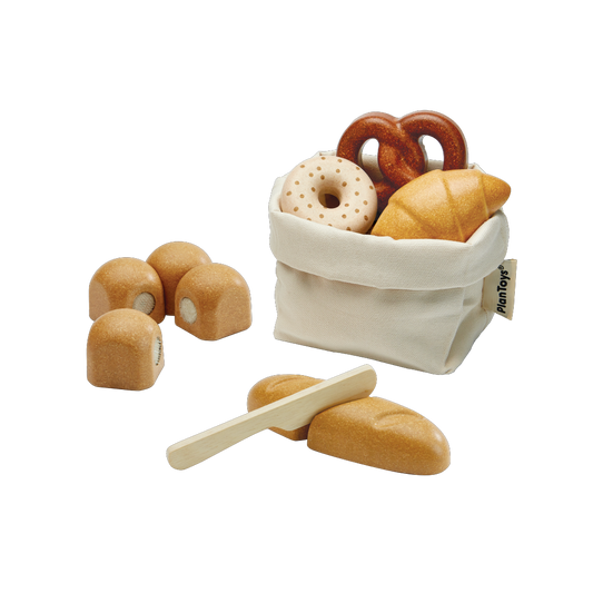 Set of wooden toy bread and pastries with a white bag on a white background