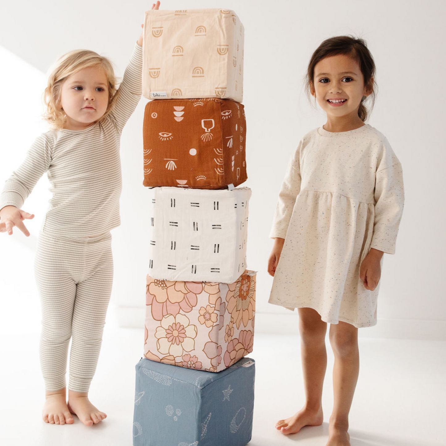 Two children playing with patterned blocks on a white background