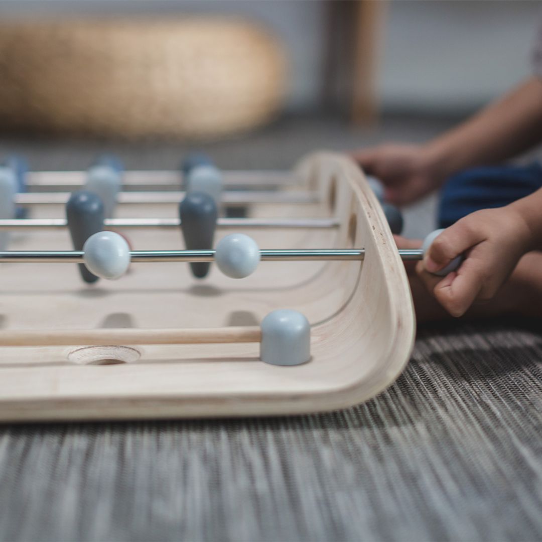 Foosball table with a child's hand interacting with one of the rods.