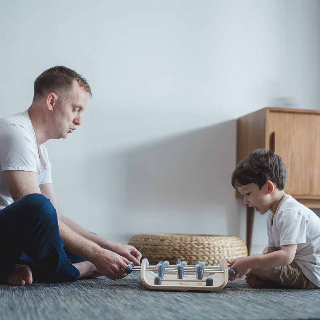 Man and child playing with a small board game on the floor.