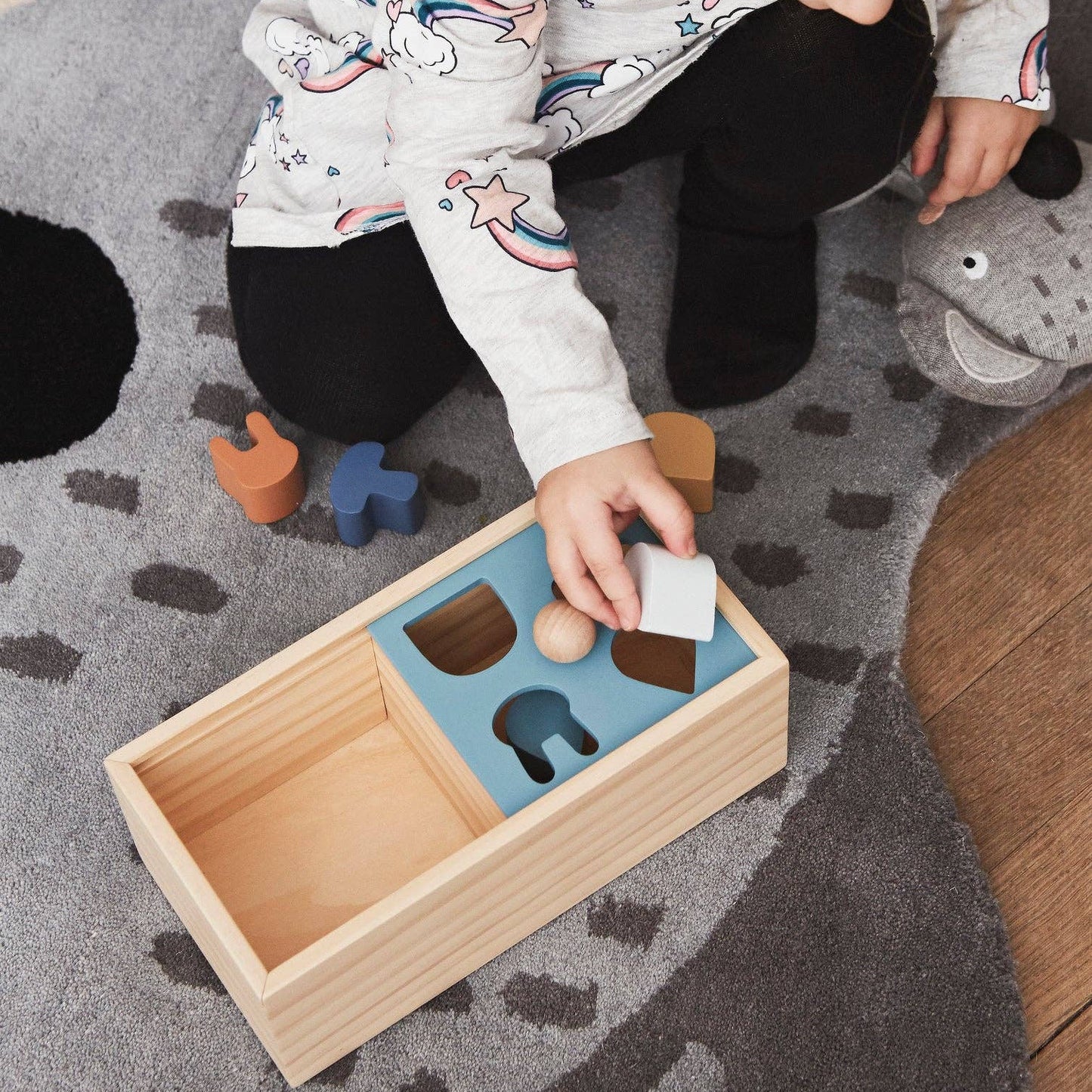 Child playing with a wooden puzzle toy on a rug