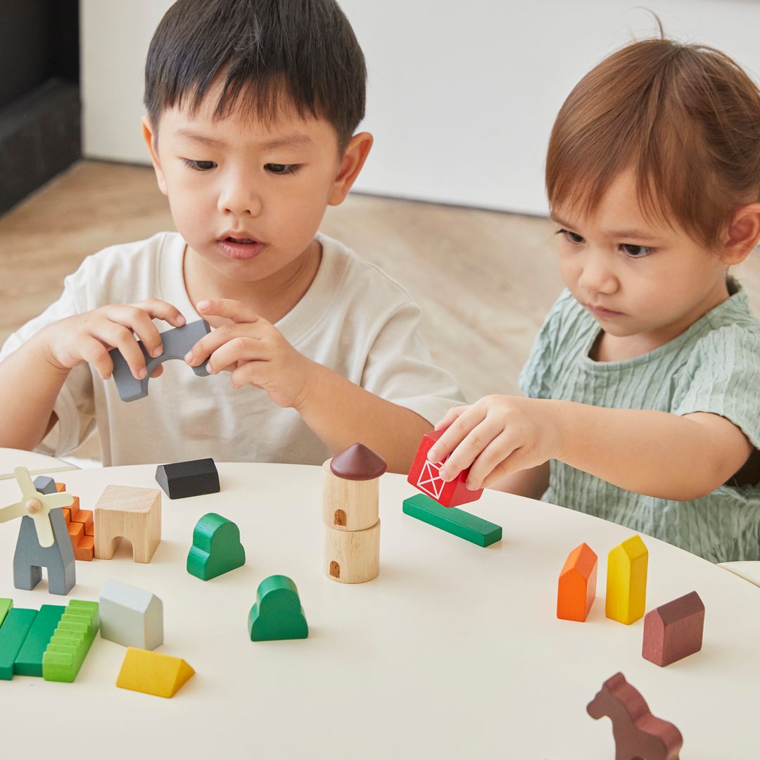 Two children playing with colorful wooden blocks on a table.