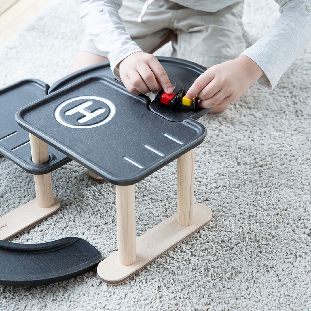 Child playing with a toy road setup on a carpeted floor