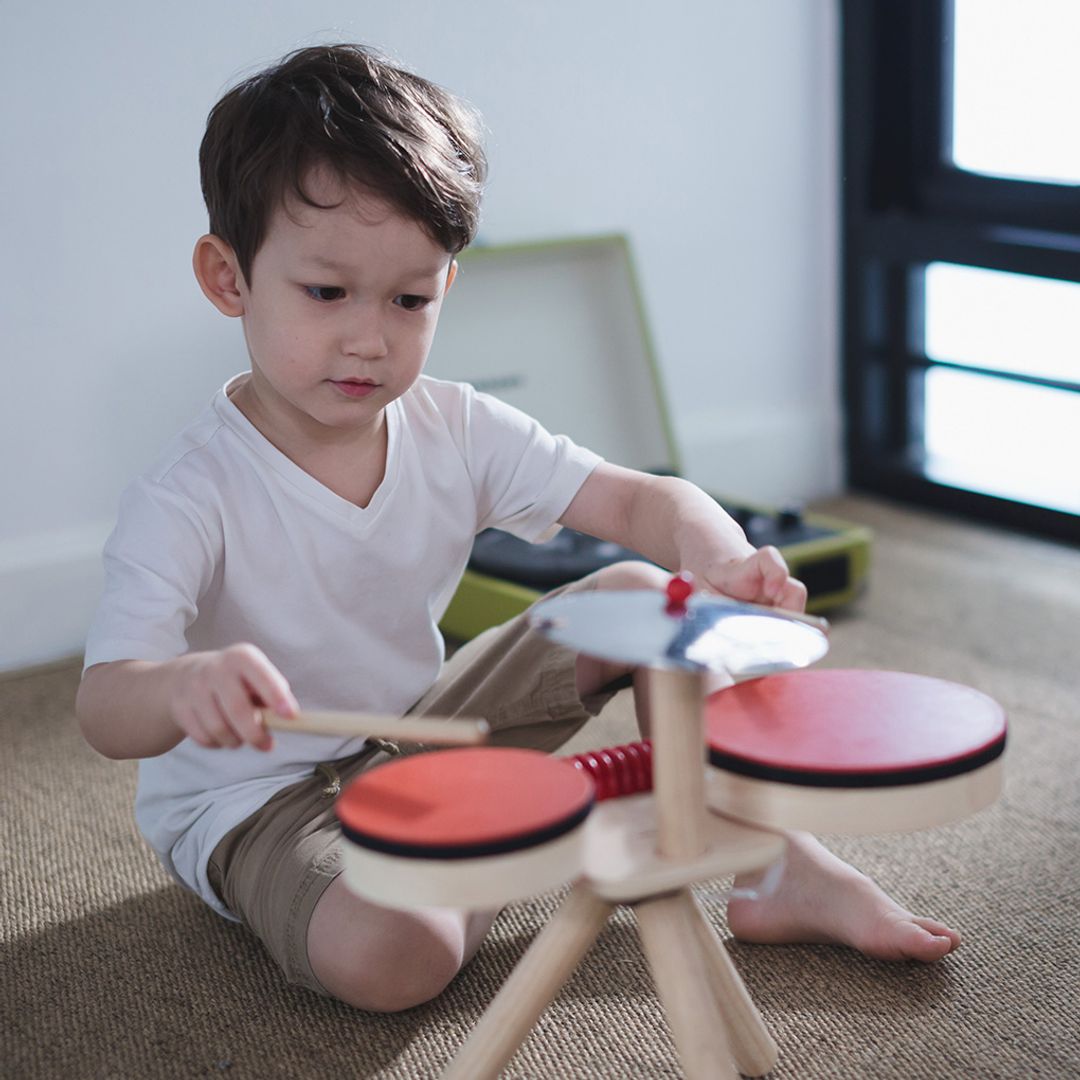 Child playing with a toy drum set on the floor
