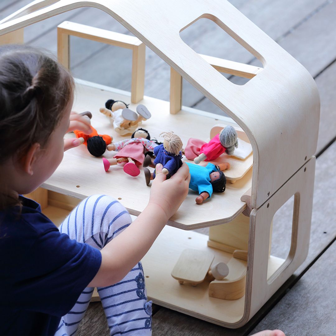 Child playing with dolls on a wooden toy house