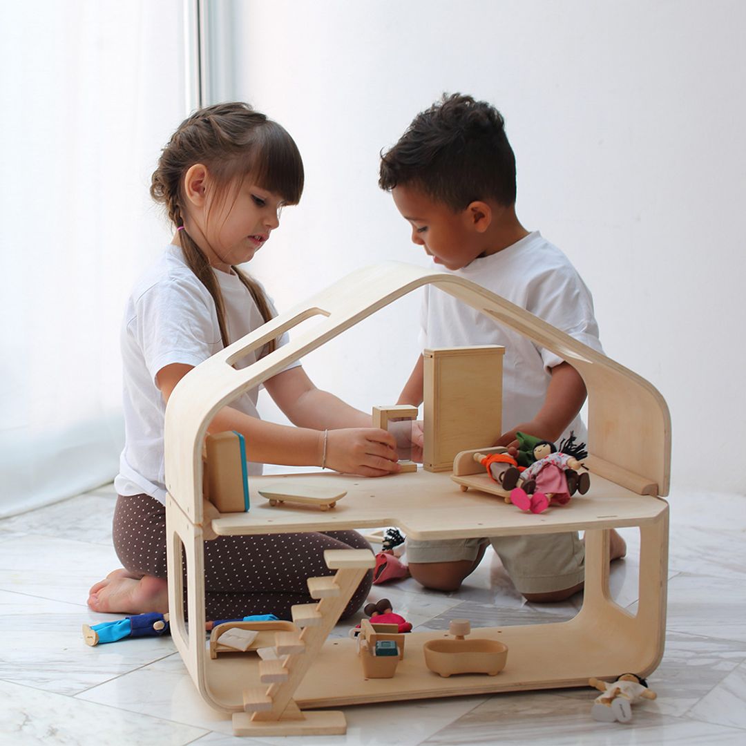 Two children playing with a wooden toy set on a white floor.