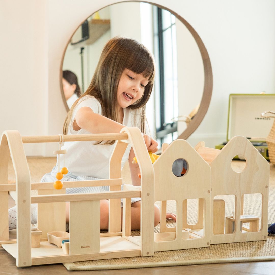 Child playing with a wooden toy on a light-colored floor.