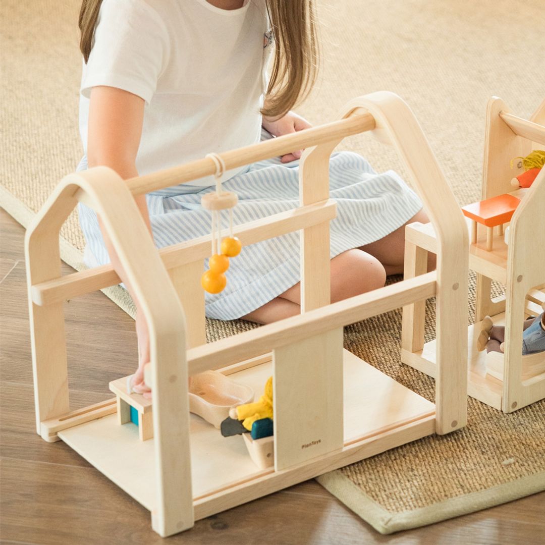Child playing with a wooden toy structure on a wooden floor.
