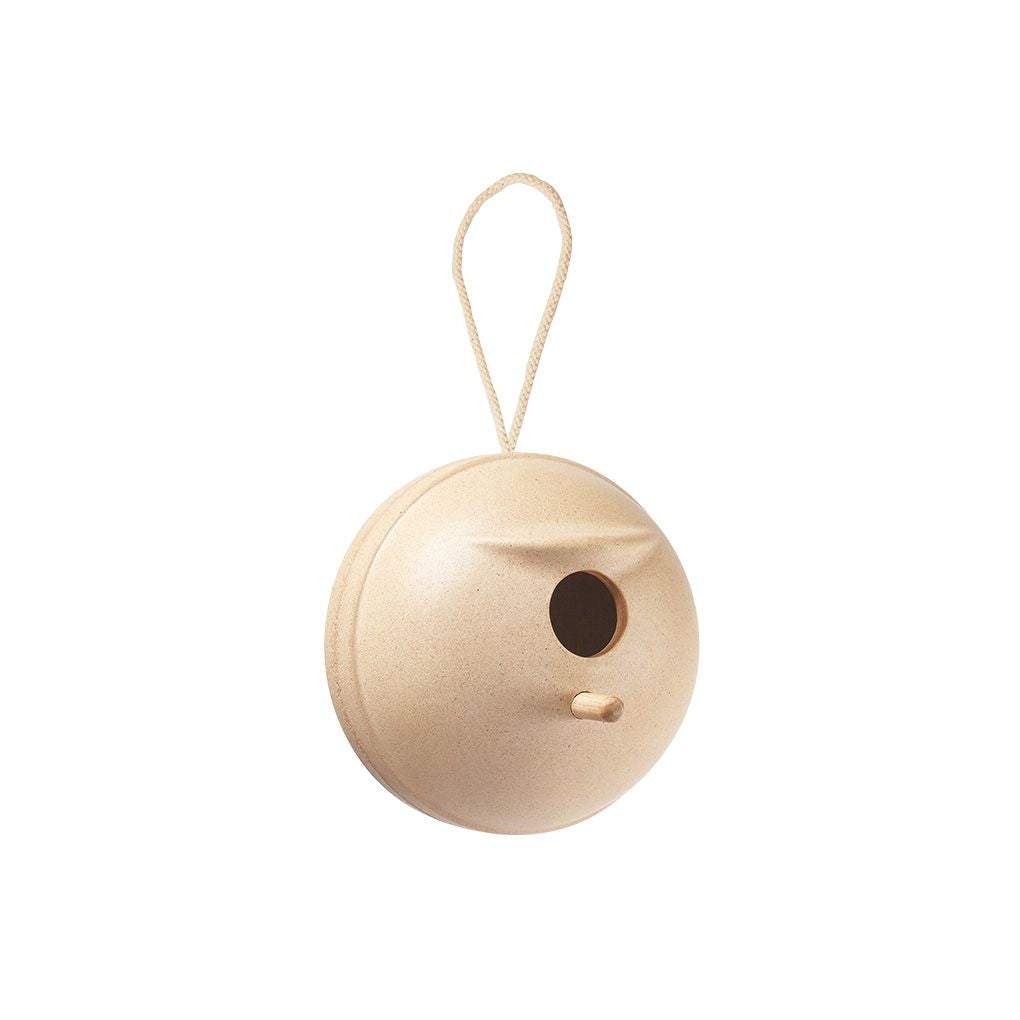 Wooden birdhouse with a round shape and a small entrance hole, hanging from a string on a white background.