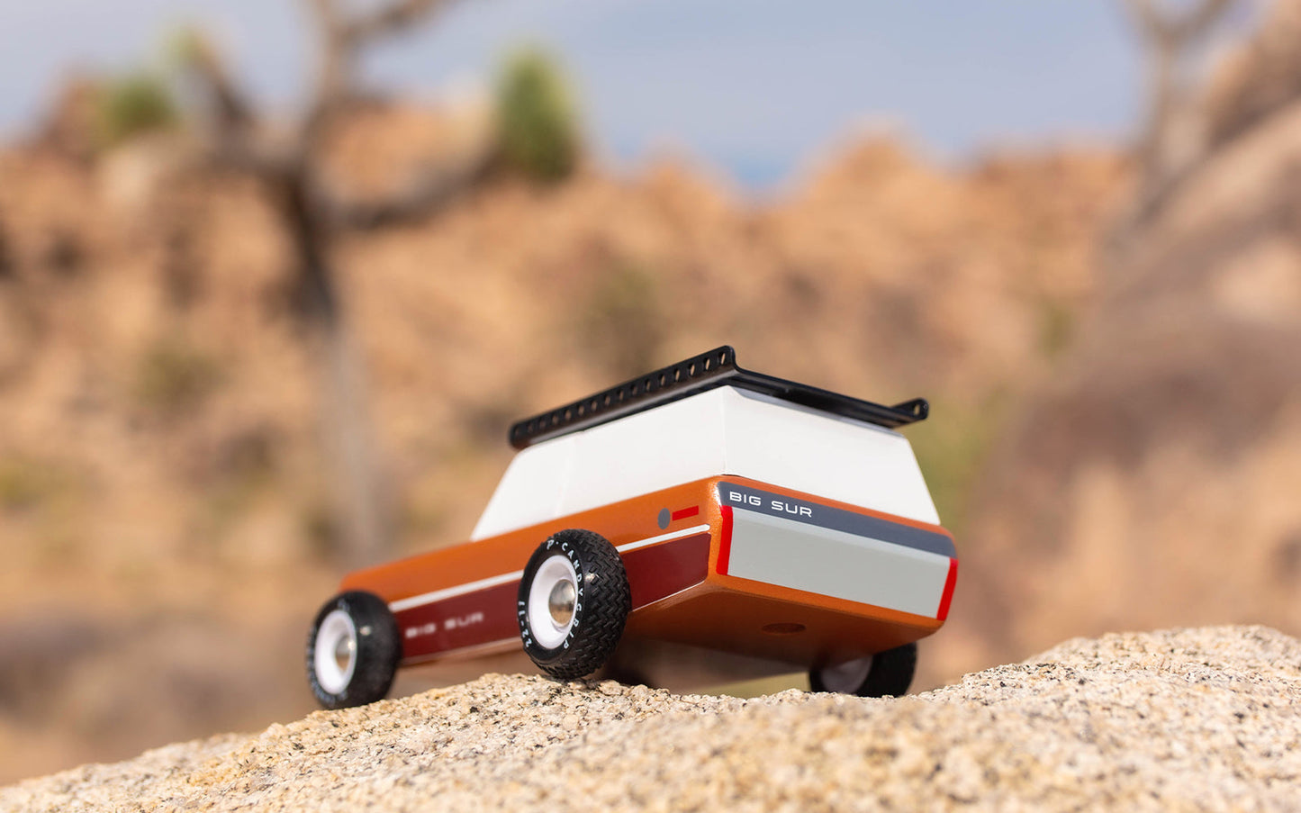 Model of a vintage lawn mower on a sandy surface with a desert landscape in the background