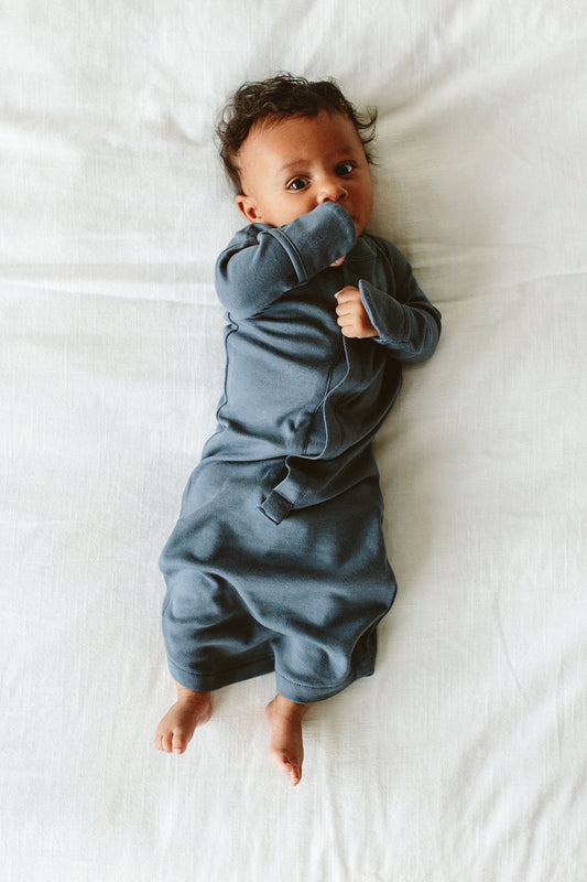 Baby in a blue onesie lying on a white surface