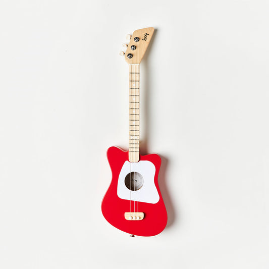 Red toy guitar with a white pickguard on a light gray background