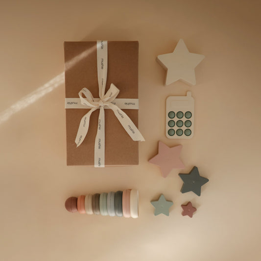 Gift box with ribbon, star-shaped decor items, and wooden rings on a beige background