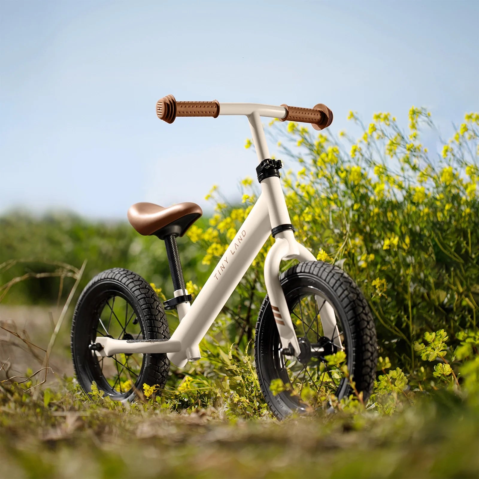 White balance bike with brown handlebar and seat in a field of yellow flowers