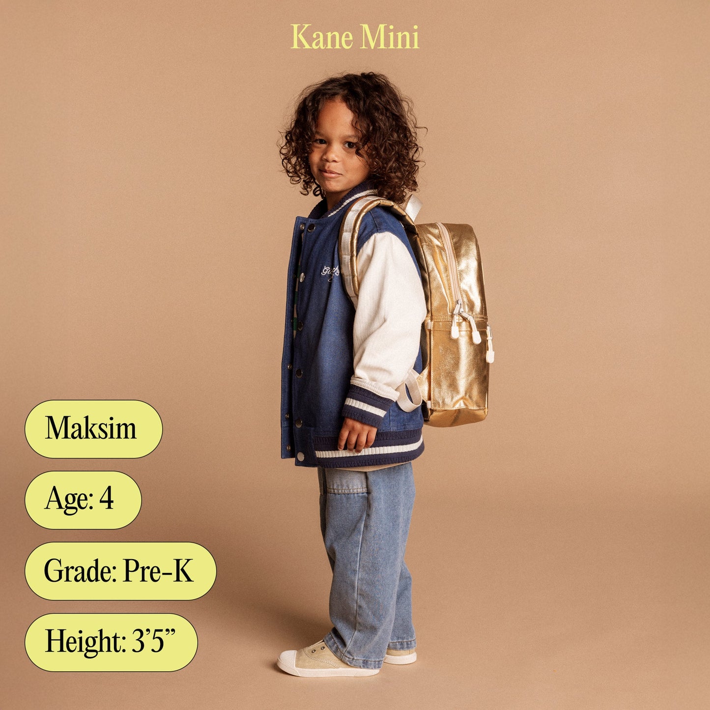Child wearing a blue jacket and jeans with a gold backpack on a beige background, featuring the brand 'Kane Mini'.