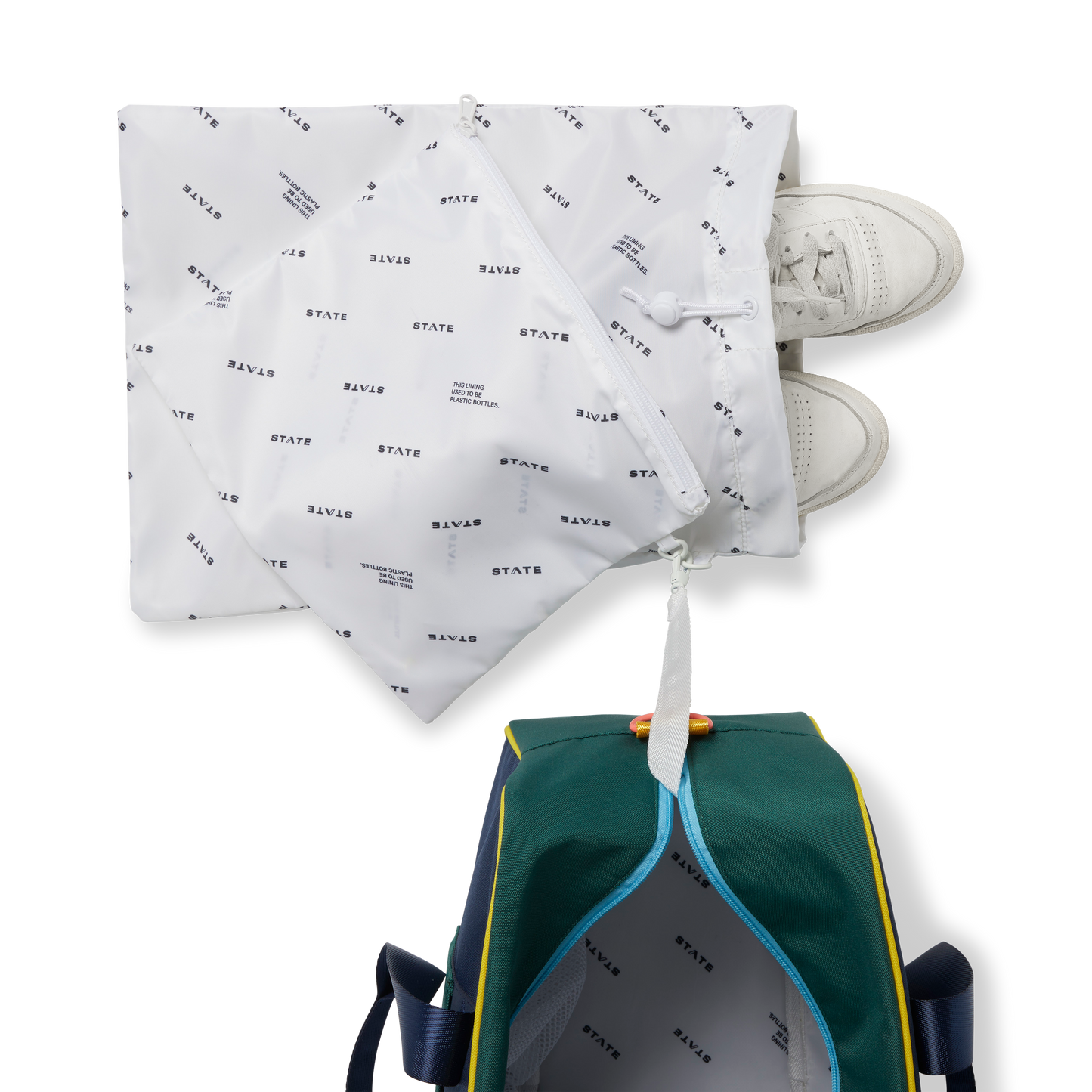 White drawstring bag with black text, white sneakers, and a green backpack on a white background
