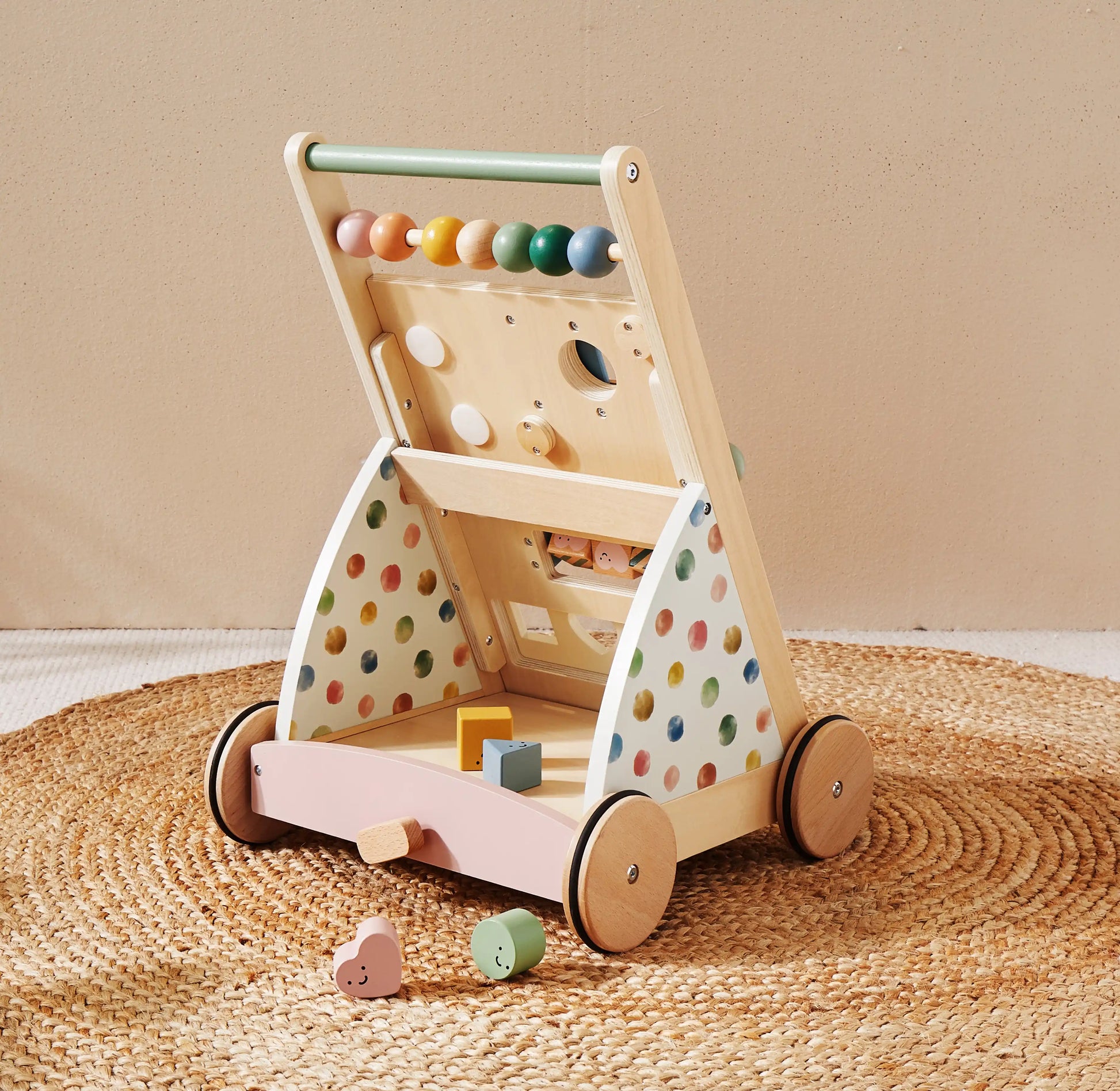 Wooden toy with colorful polka dot design on wheels, featuring various educational toys on a beige background.