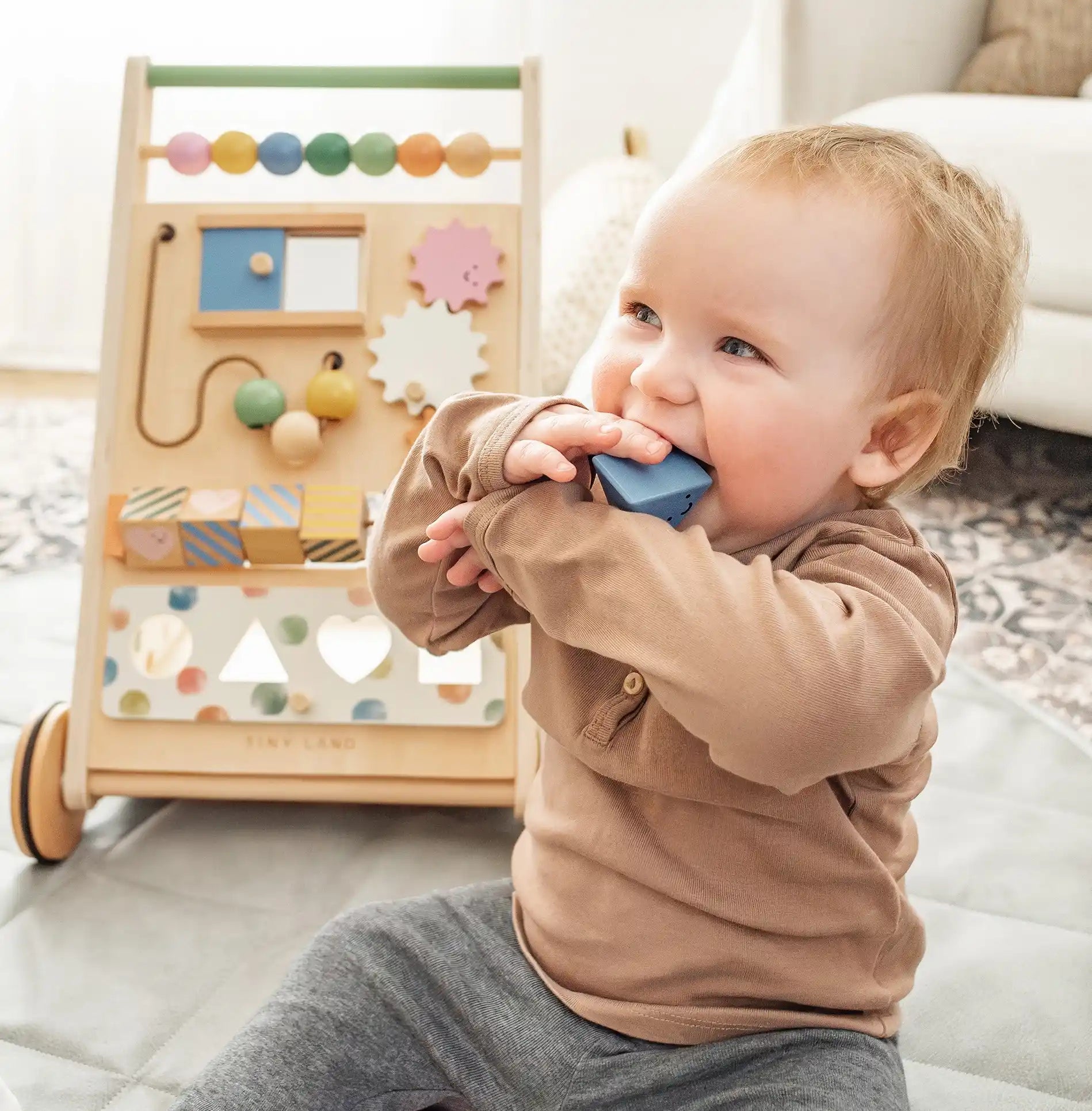 Baby playing with a wooden toy on a light-colored surface