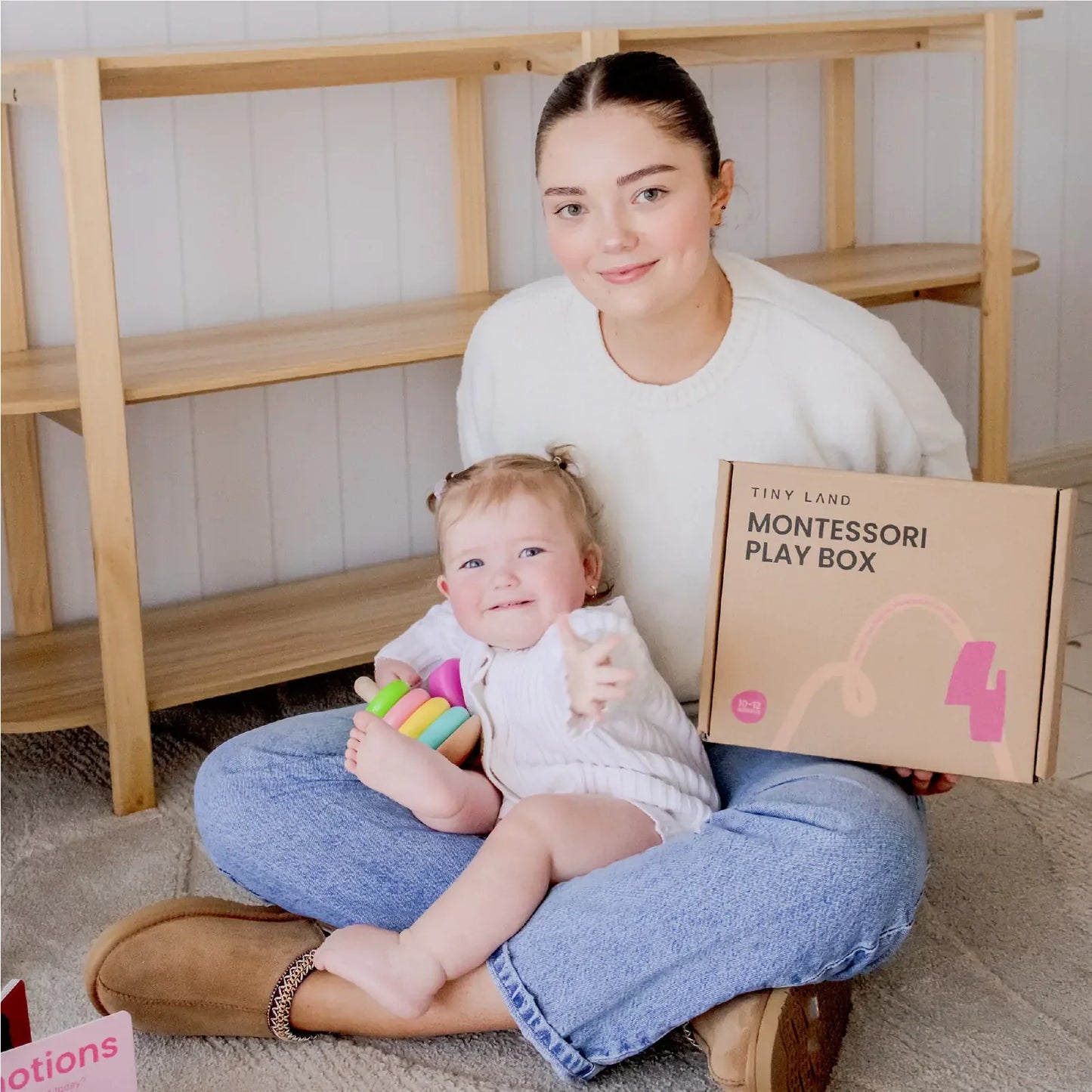 Woman holding a child and a Montessori play box in a home setting