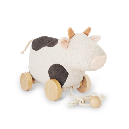 Toy cow with wooden wheels on a white background