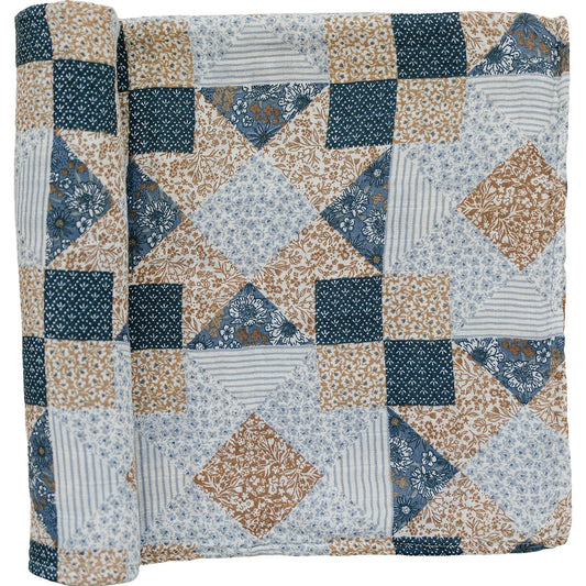 Patchwork quilt with blue, beige, and white patterns on a plain background