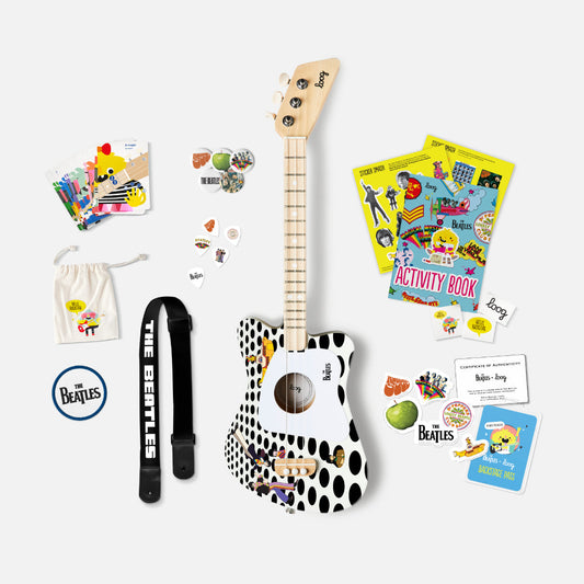 Mini guitar with polka dot design, strap, and accessories on a white background