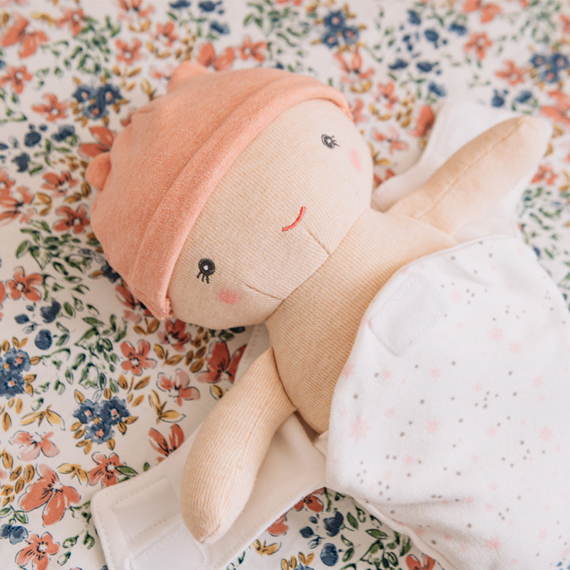 Stuffed doll with a pink hat on a floral fabric background