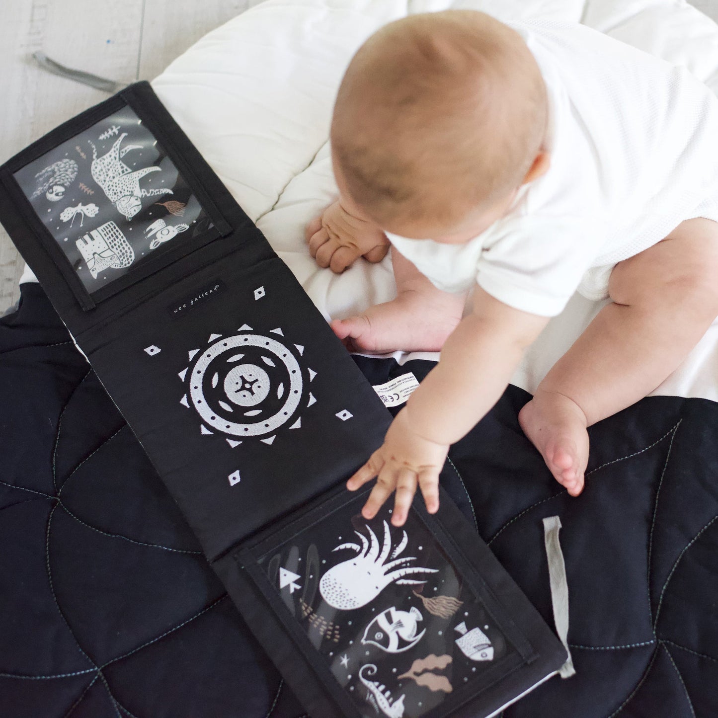 Baby interacting with a black and white patterned book on a bed
