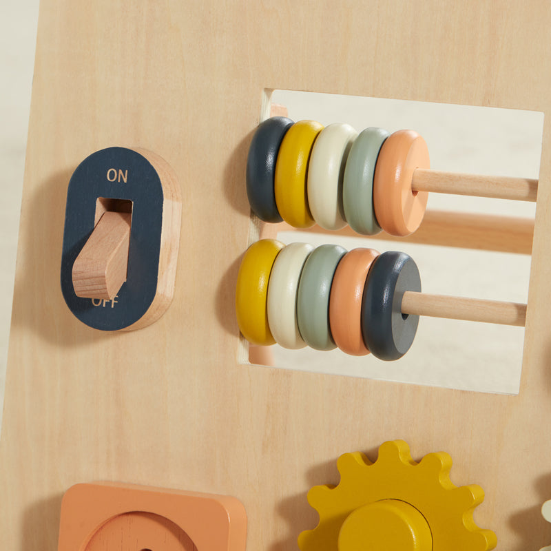 Wooden educational toy with colorful gears and a switch on a beige background