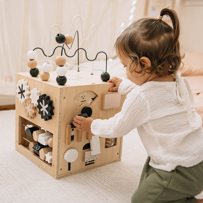 Child playing with a wooden activity cube in a home setting