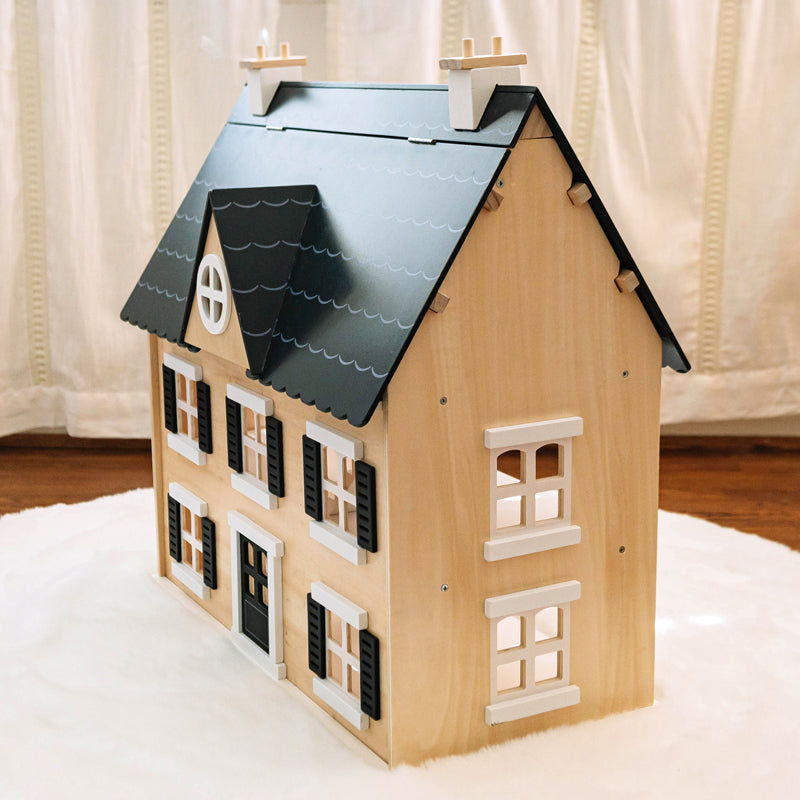 Wooden model of a house with a black roof on a white surface