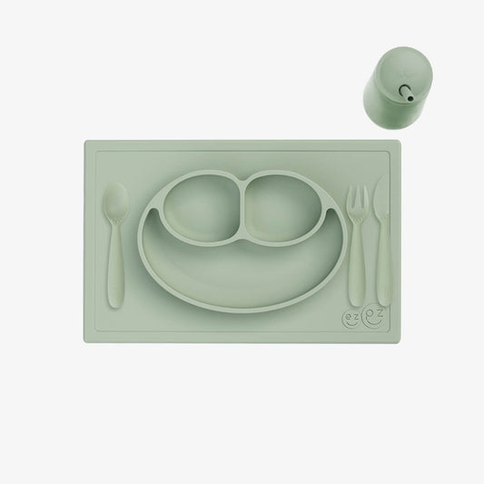 Green silicone placemat with plate, spoon, fork, and cup on a white background
