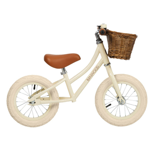 Beige balance bike with a brown seat and basket on a white background