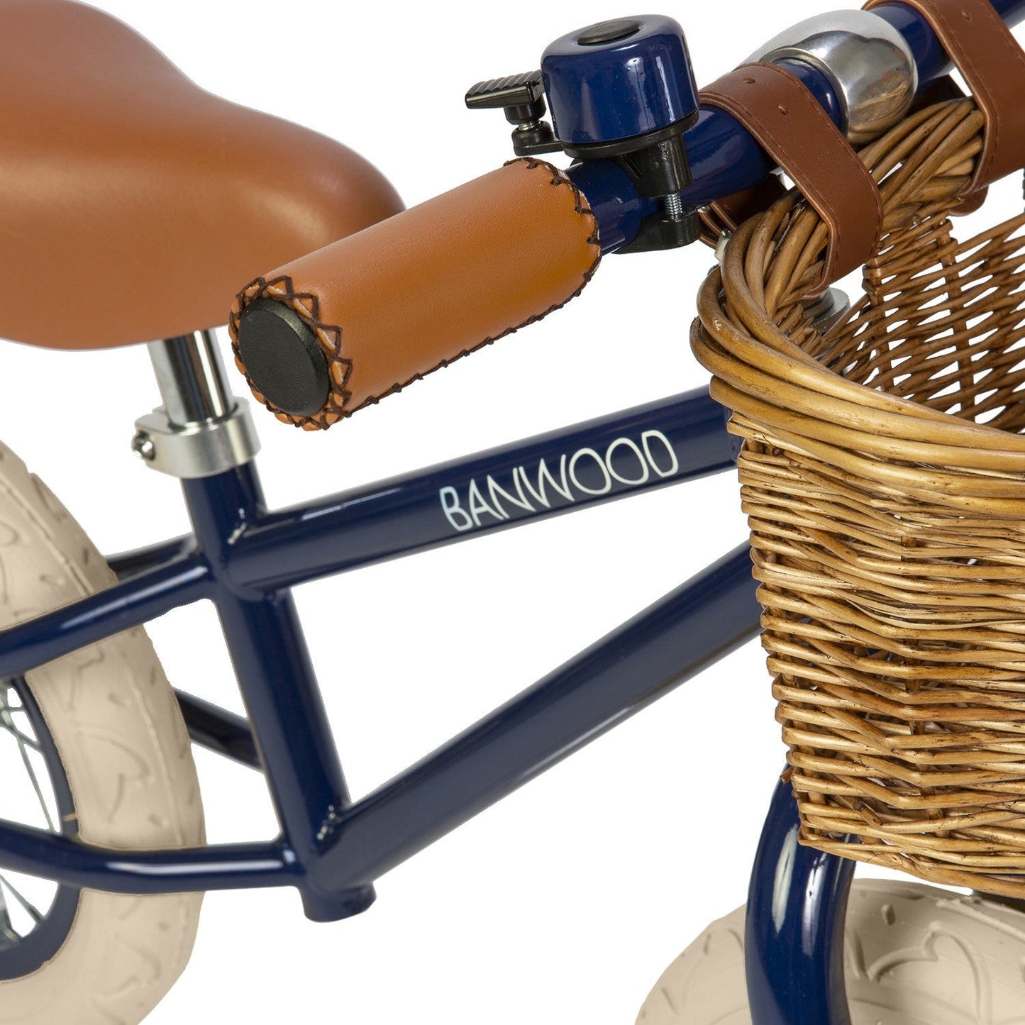 Navy balance bike with brown basket and seat on a white background