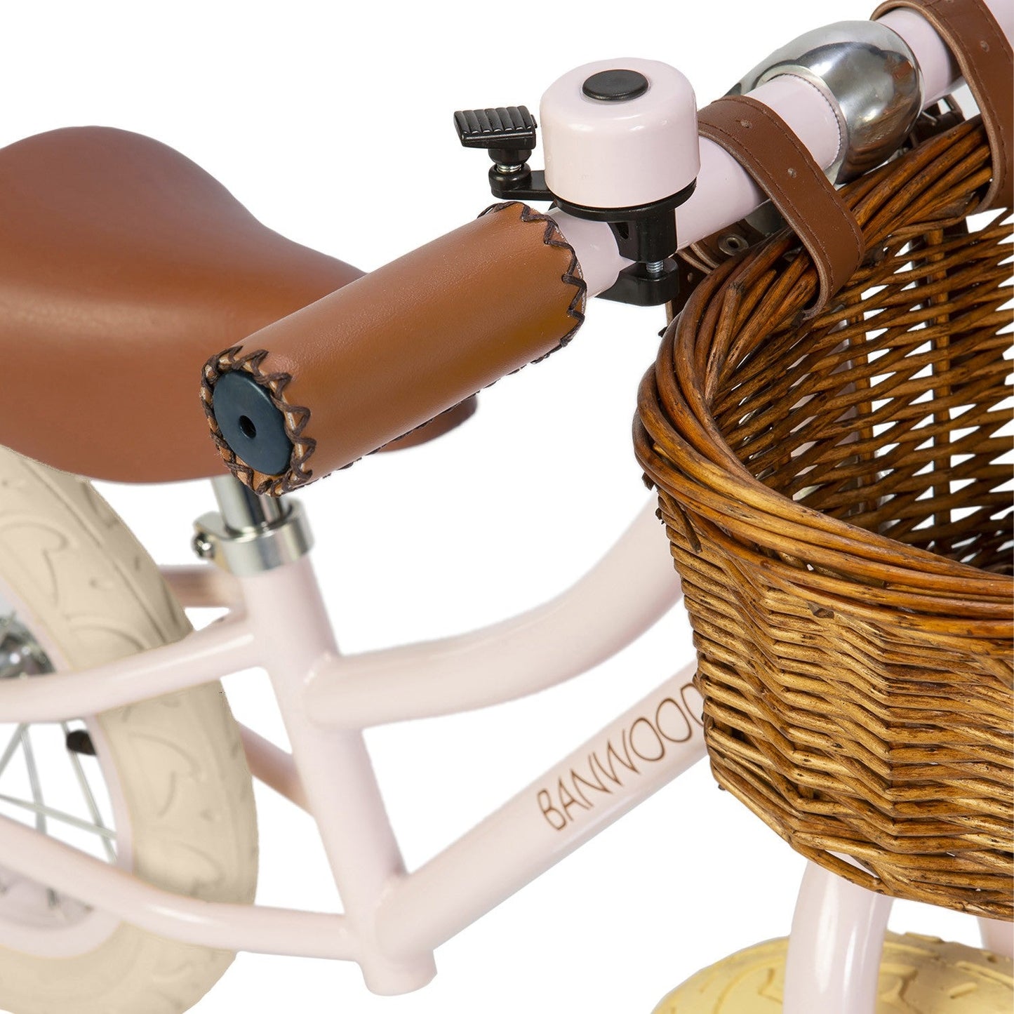 Close-up of a children's bike with a wicker basket and brown seat on a white background.