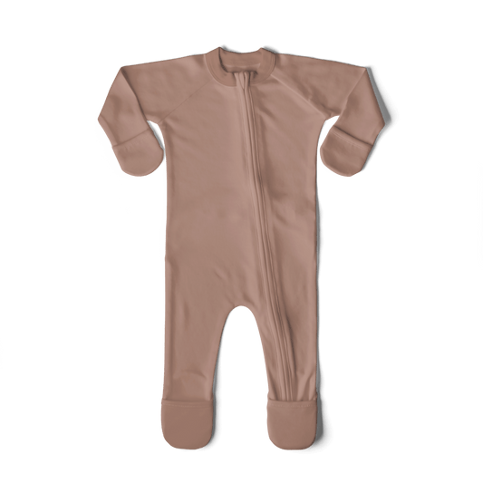 Newborn baby in a pink outfit being held by a person on a textured surface